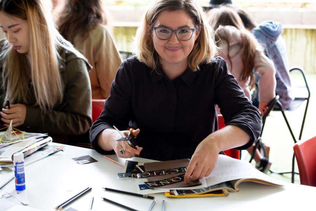 People sitting at a table, cutting pictures and titles out of magazines.