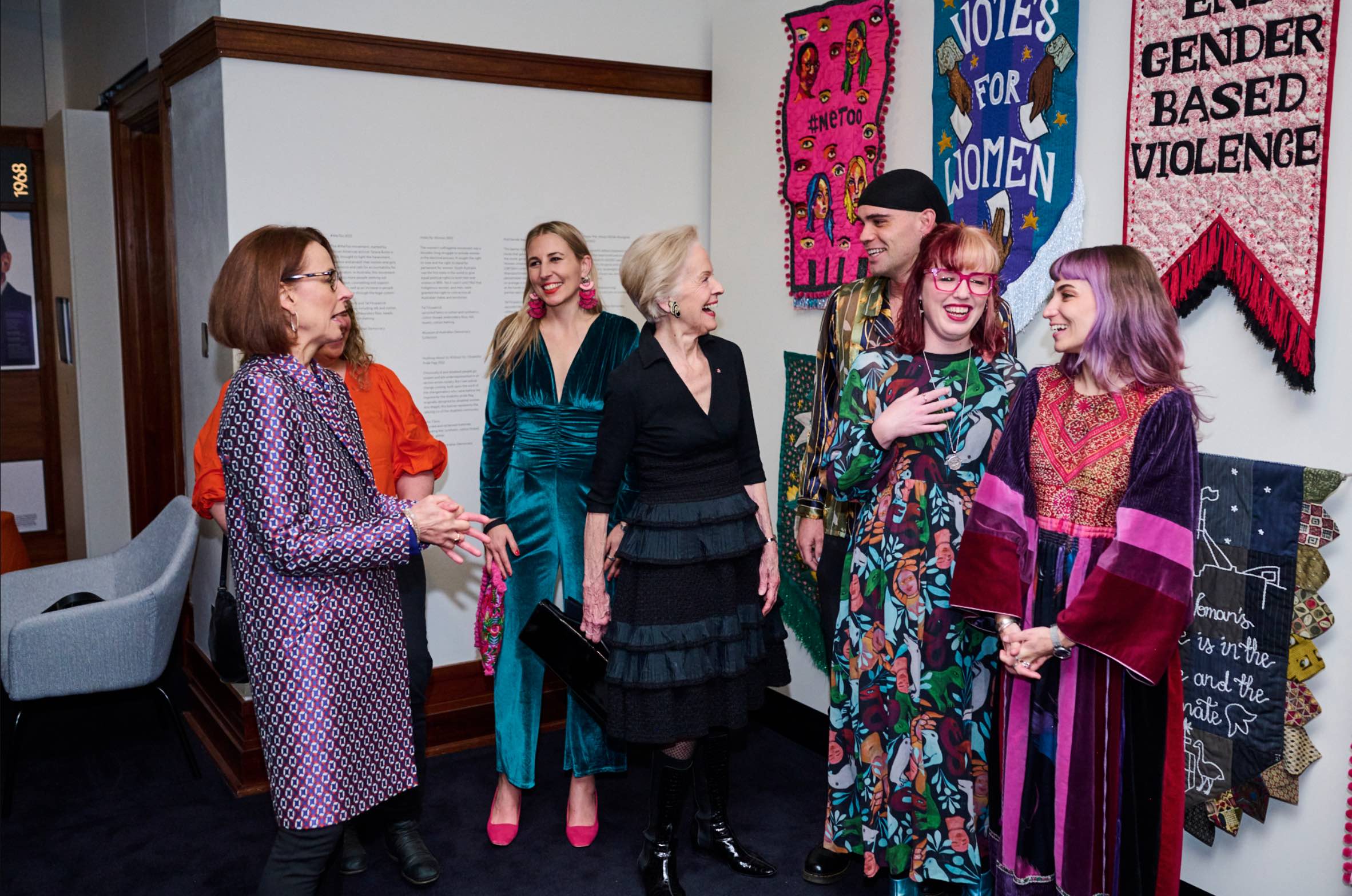 Quentin Bryce chats to artists in front of embroidered banners at the front of the Changemakers exhibition at MoAD.