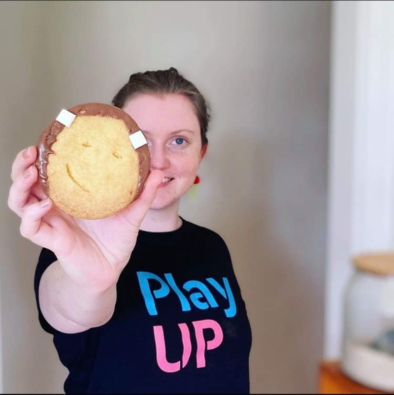 A PlayUP facilitator holds up a biscuit. 