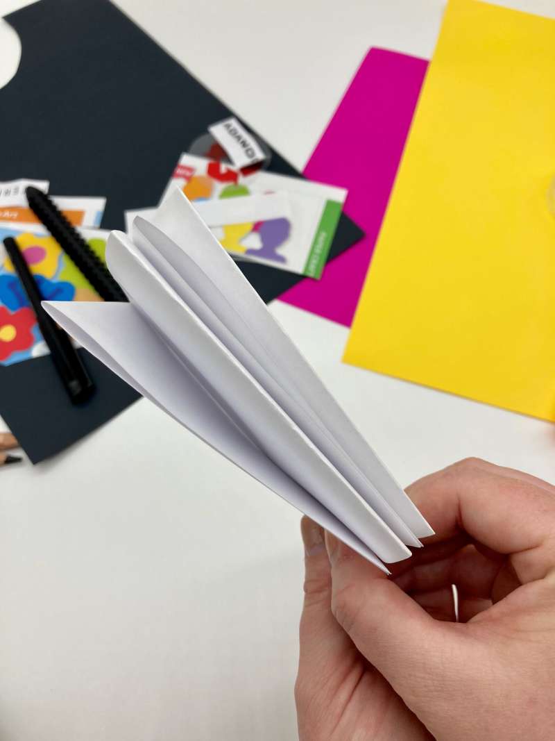 A hand holding paper folded to look like a booklet with pages. 