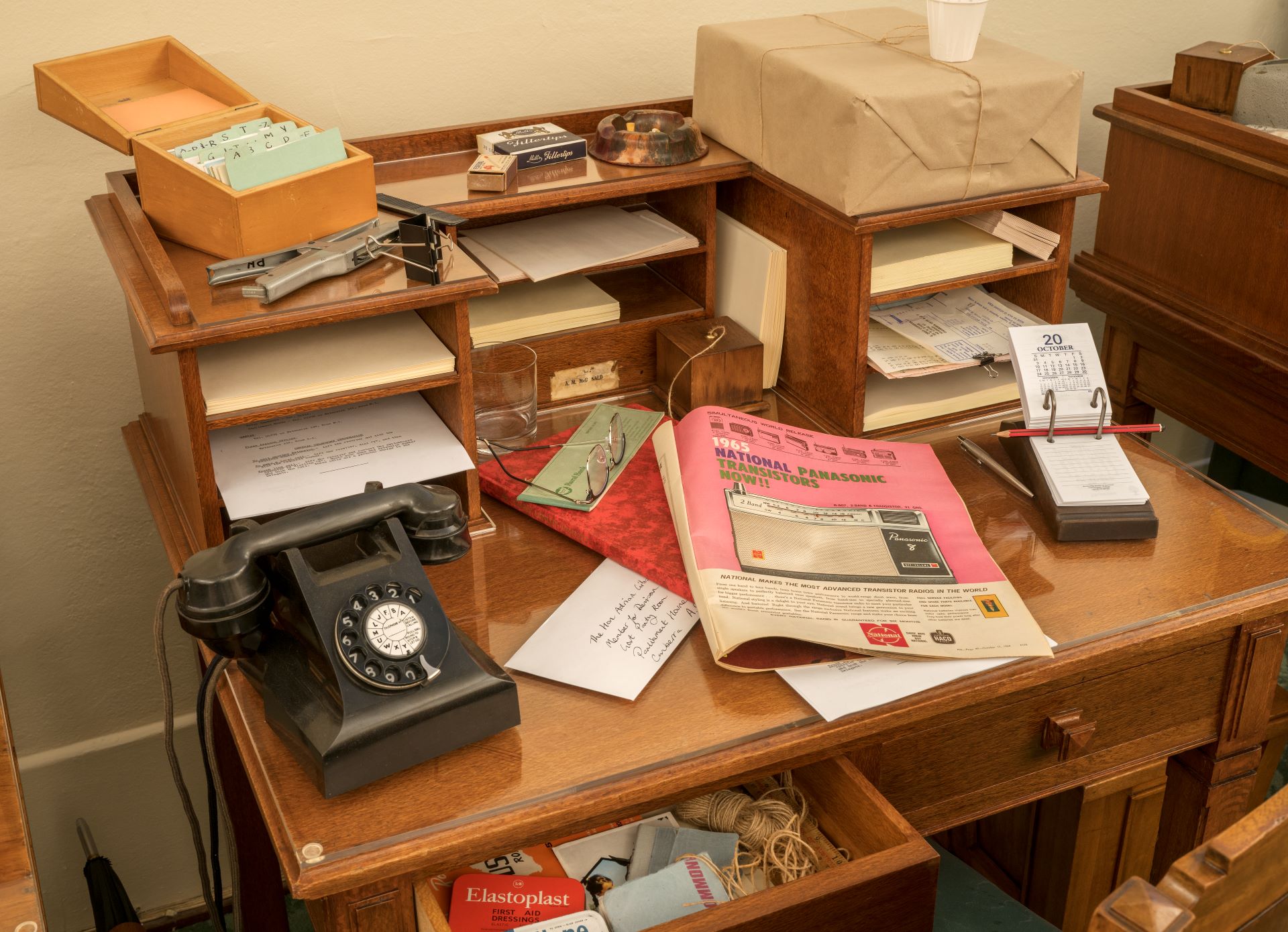 In earlier times, parliamentarians who had not been allocated a desk in an office would use one in the Party Room.
Photograph of a table covered in an assortment of prop historical objects in the Government Party Room