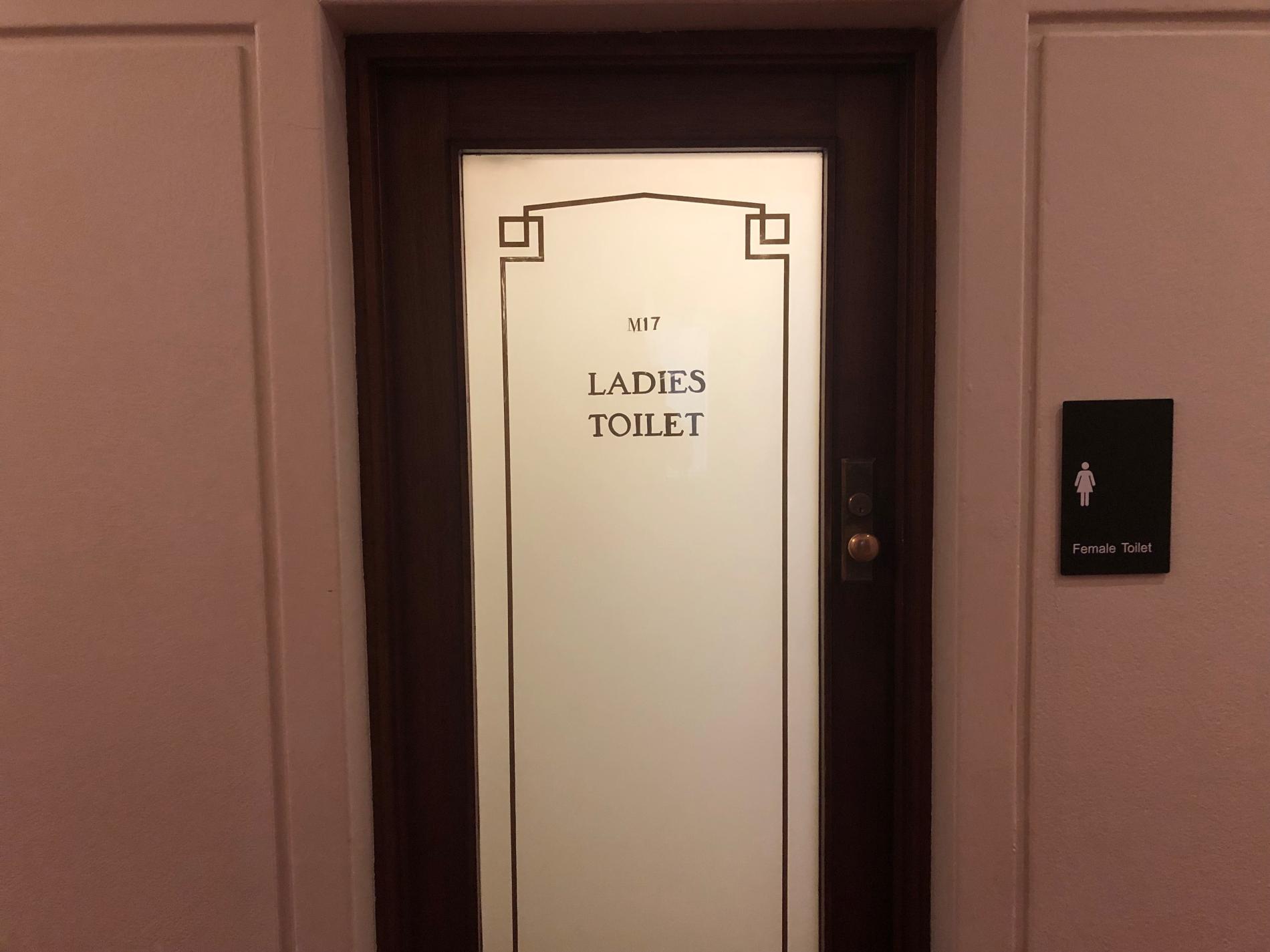 A wooden door with an ornate frosted glass panel with the words M17 Ladies Toilet.