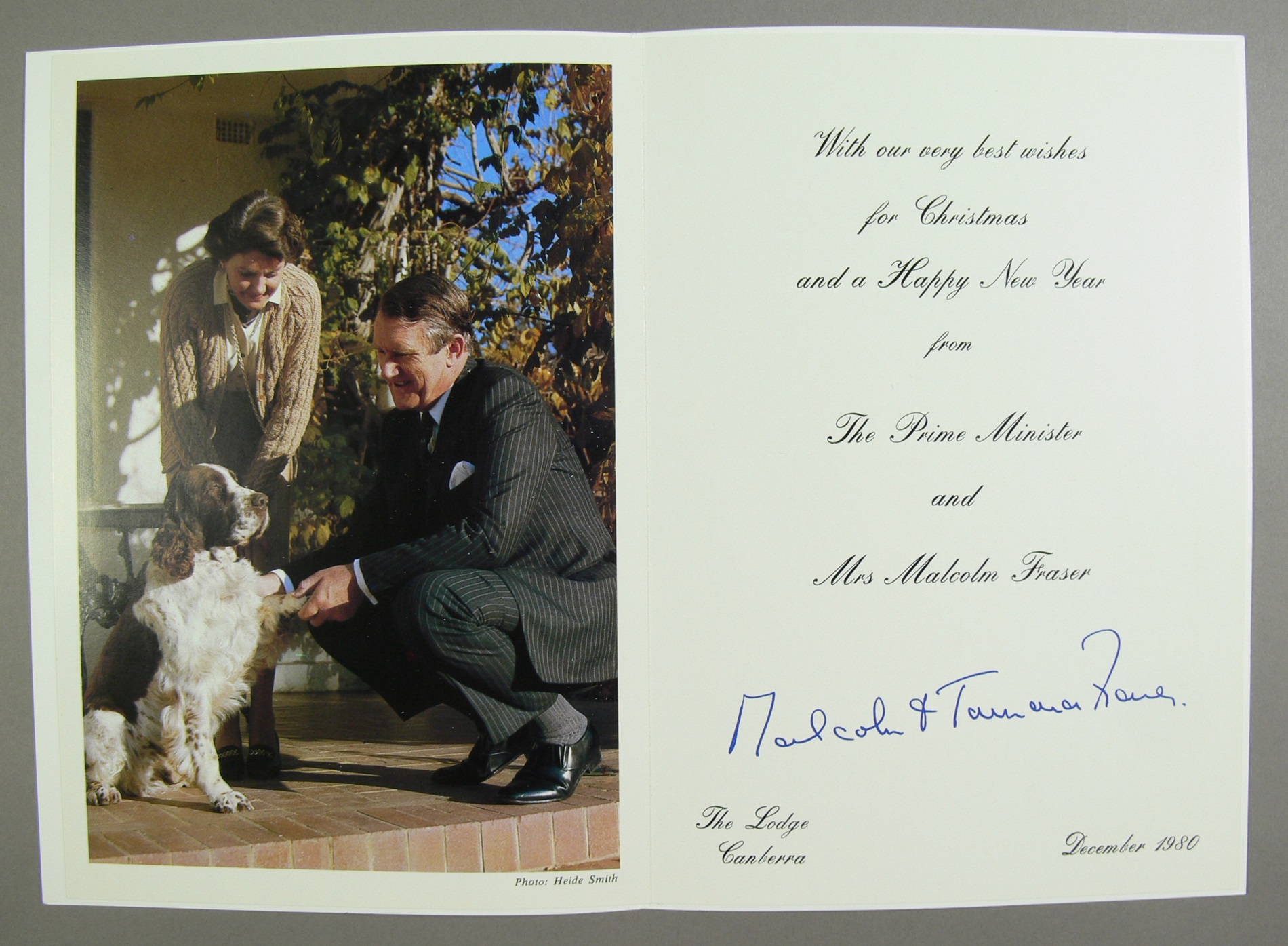 A Christmas card featuring a photo of Malcolm and Tamie Fraser with their dog, Droopy, a brown and white English springer spaniel.