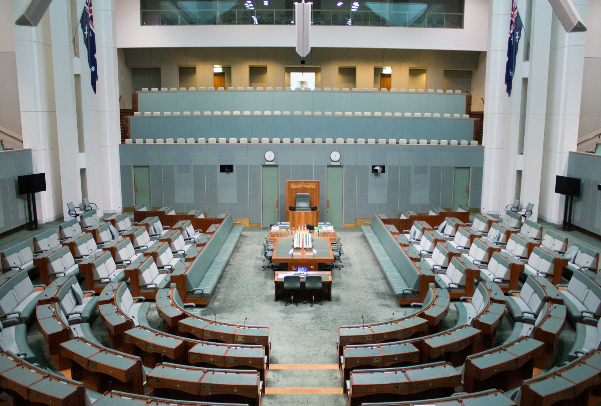 The House of Representatives, a room with grey-green furnishings, with benches arranged in a horse-shoe shape around a central long bench and chair.