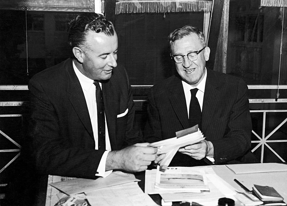 Arthur Calwell and Gough Whitlam are both holding and looking at some papers.