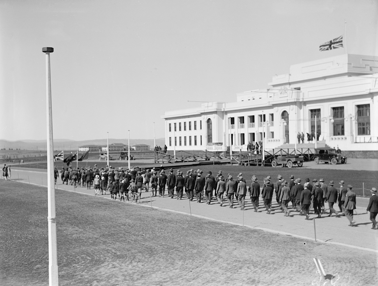 A parade marches in front of Parliament House. 