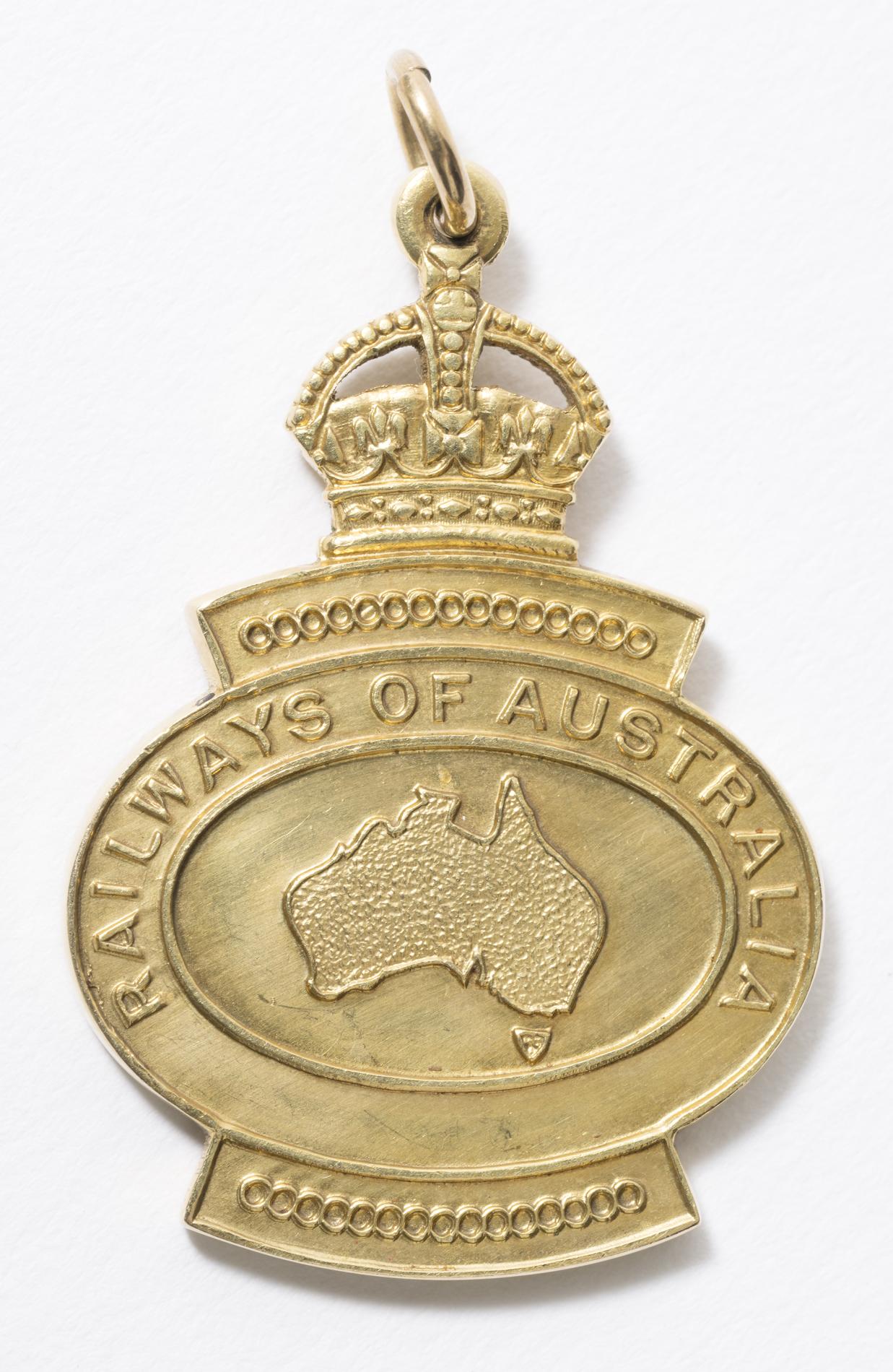 One side of a gold pocket-sized medallion with a crown at the top and the text 'Railways of Australia' above a map outline of Australia.