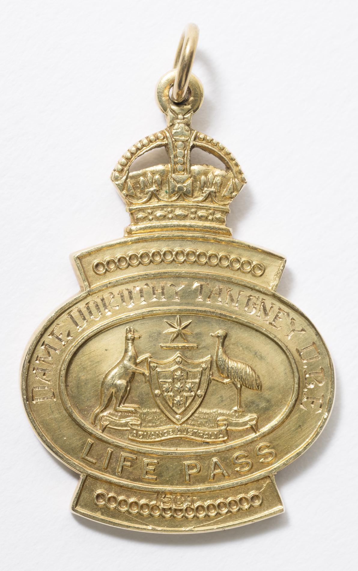 One side of a gold pocket-sized medallion with a crown at the top and the text 'Dame Dorothy Tangney D.B.E.' and 'Life Pass' around the Commonwealth Coat of Arms.