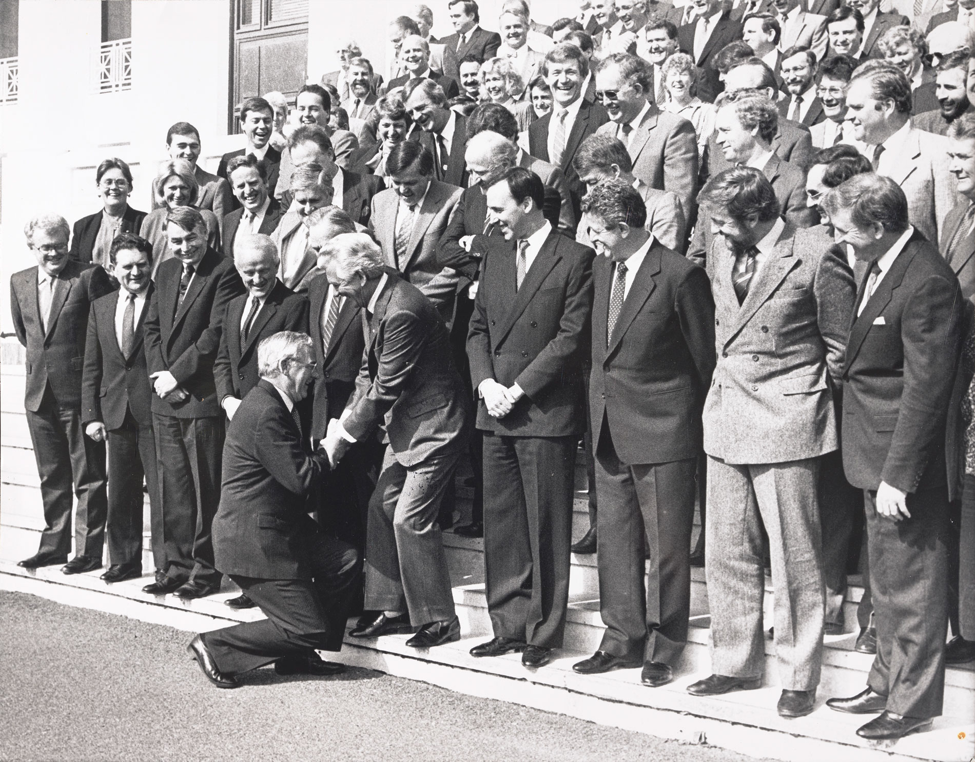 Bill Hayden curtsies to Bob Hawke who stands with other parliamentary staff on the steps of Parliament House. Bill Hayden curtsies to Bob Hawke who stands with other parliamentary staff on the steps of Parliament House.
