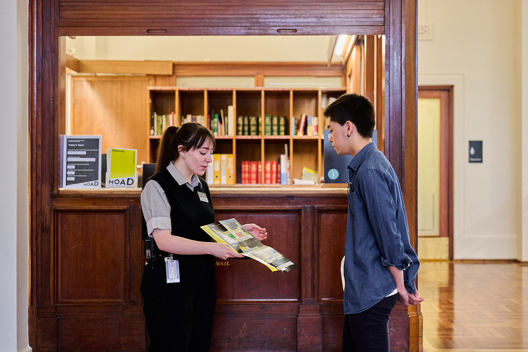 An Old Parliament House museum staff member stands in King's Hall showing a visitor a map. An Old Parliament House museum staff member stands in King's Hall showing a visitor a map.