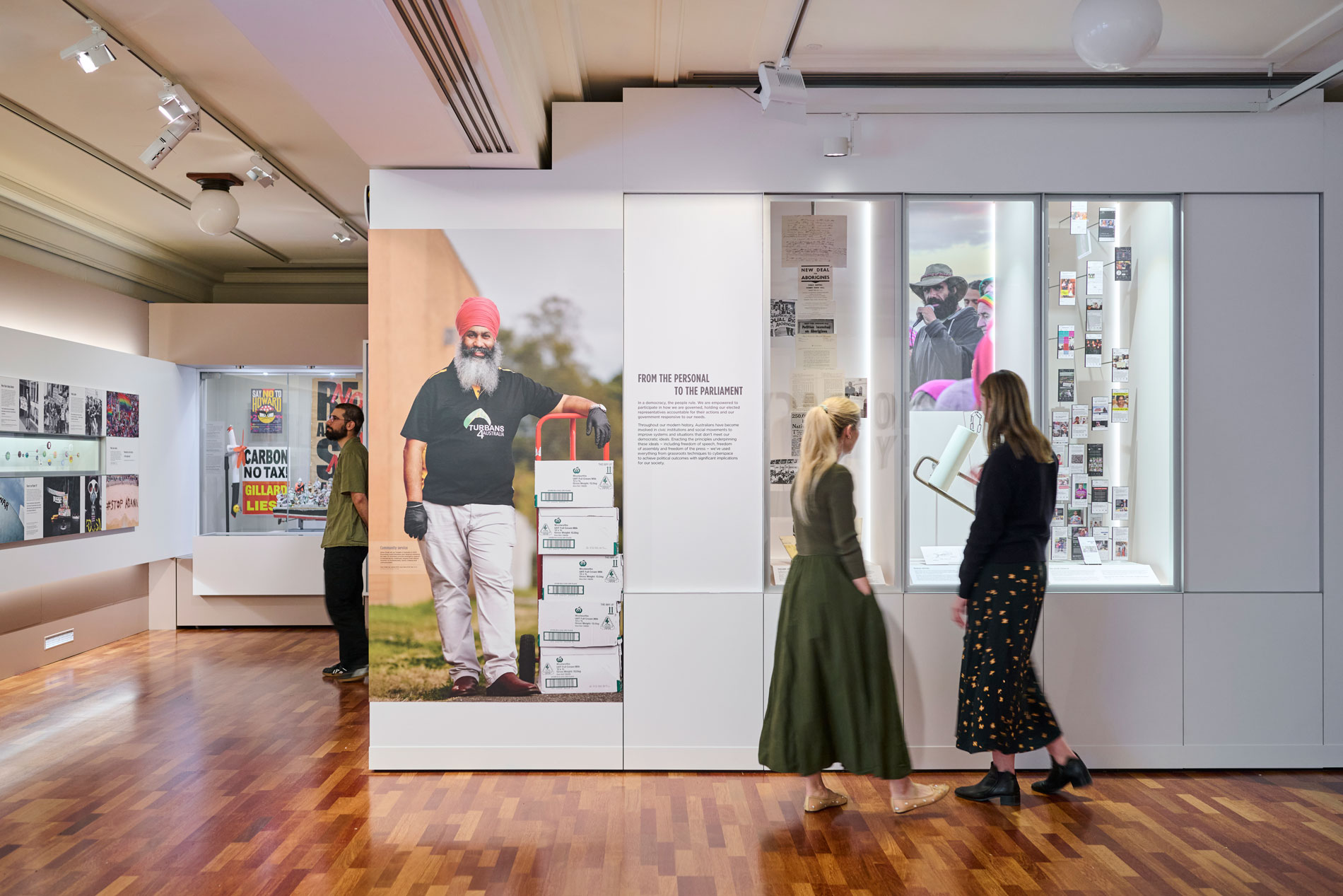 Three people read panels in the Democracy Are You In exhibit in Old Parliament House.