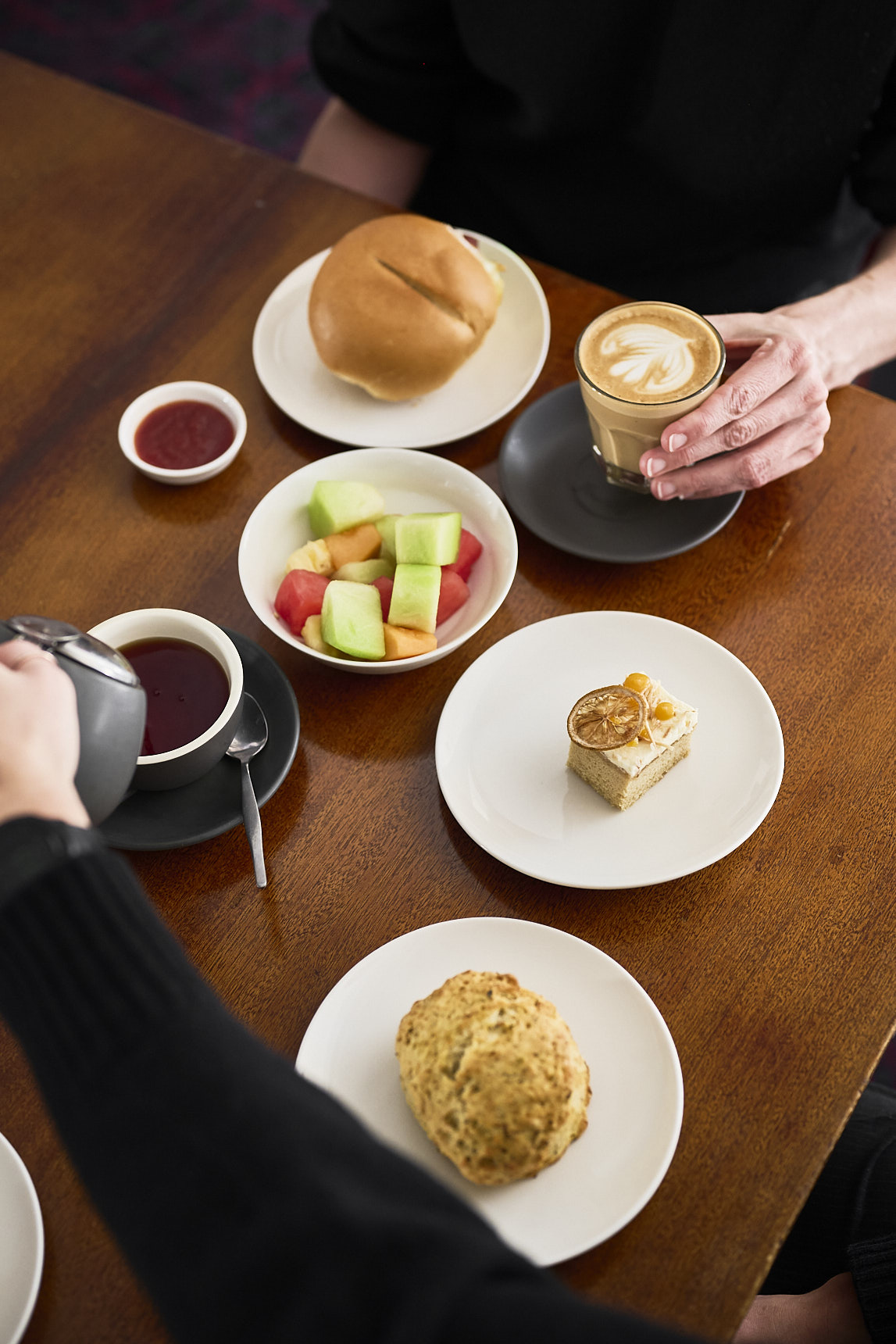 Two people enjoying coffees at the cafe at the Museum of Australian democracy, accompanied by a couple smaller plates of food.