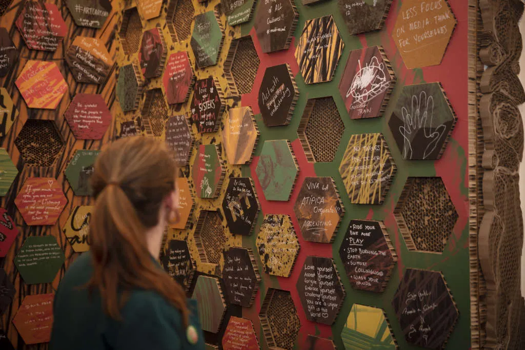 A visitor looking at a wall of honeycomb-styled blocks in the exhibition.