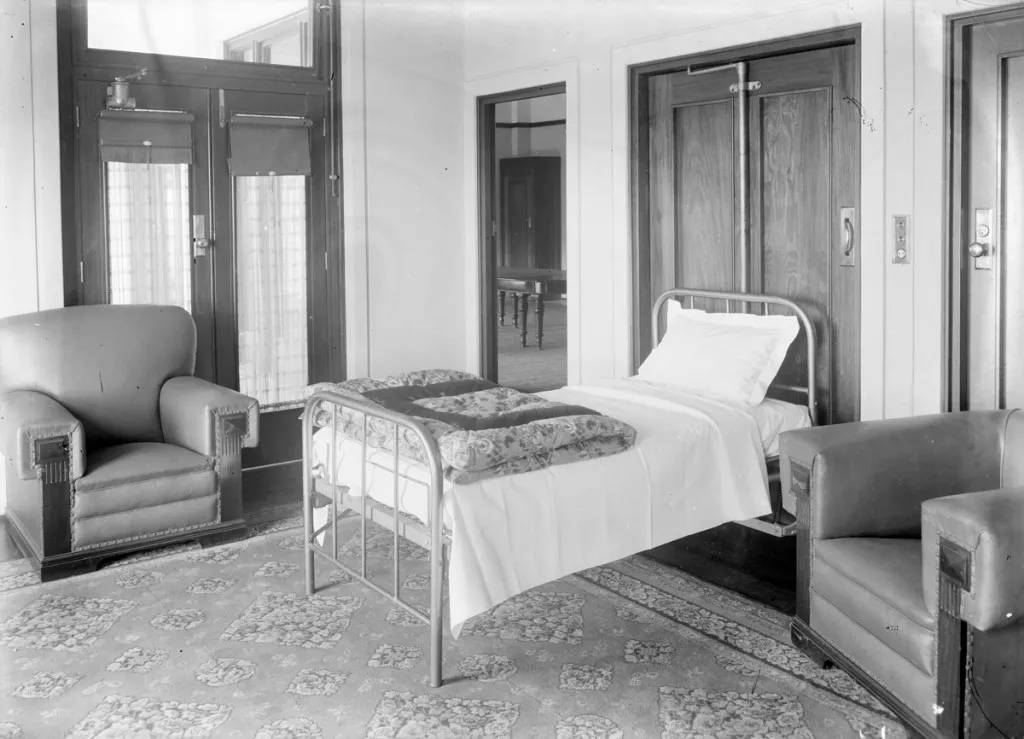 A black and white photo of a single bed in a room A black and white photo of a single bed in a room
