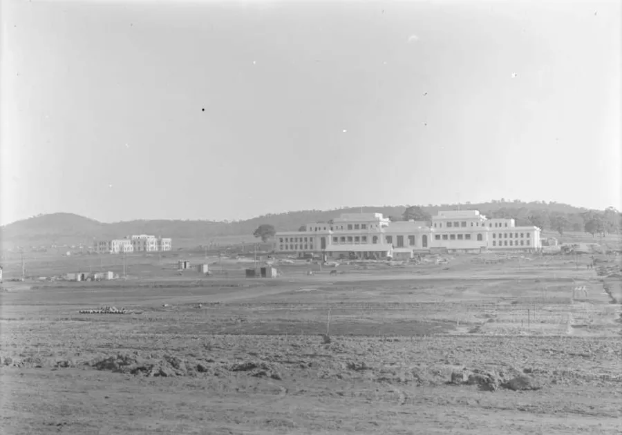 A faded black and white photograph shows the Old Parliament House building across a cleared paddock, with East Block farther away to the left.