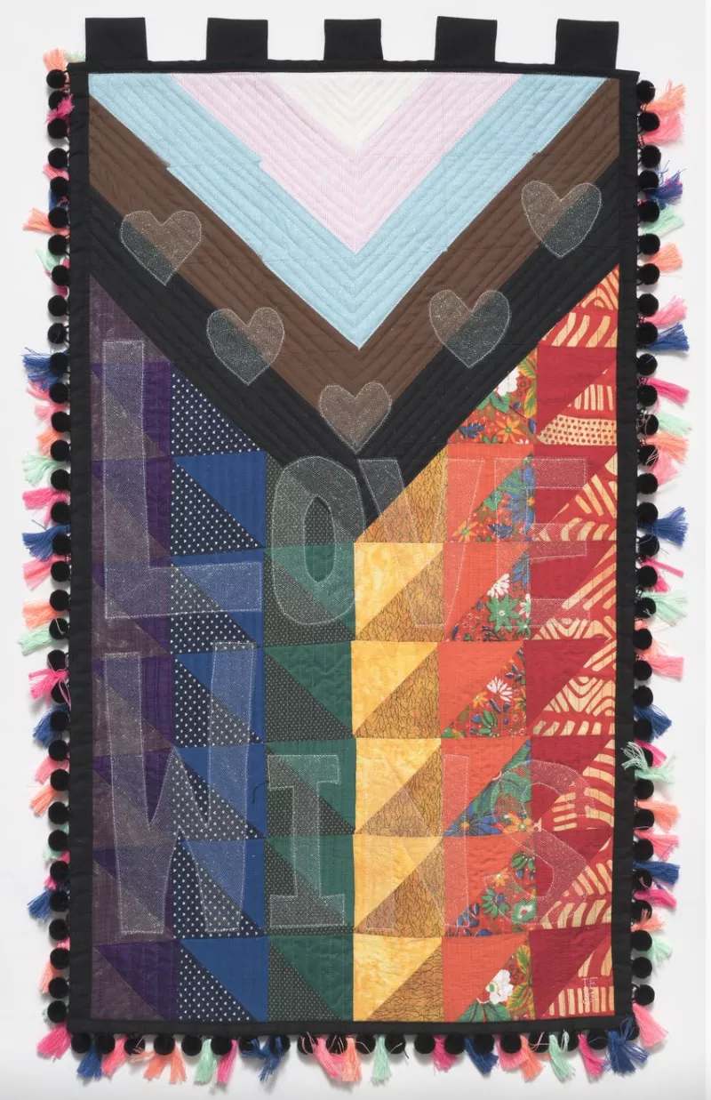 Multi-cultured rainbow tapestry containing the words 'Love wins'.