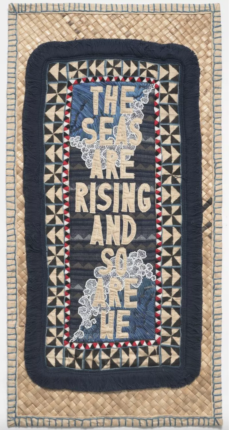 Blue, beige and black tapestry that contains the message 'The seas are rising and so are we'.