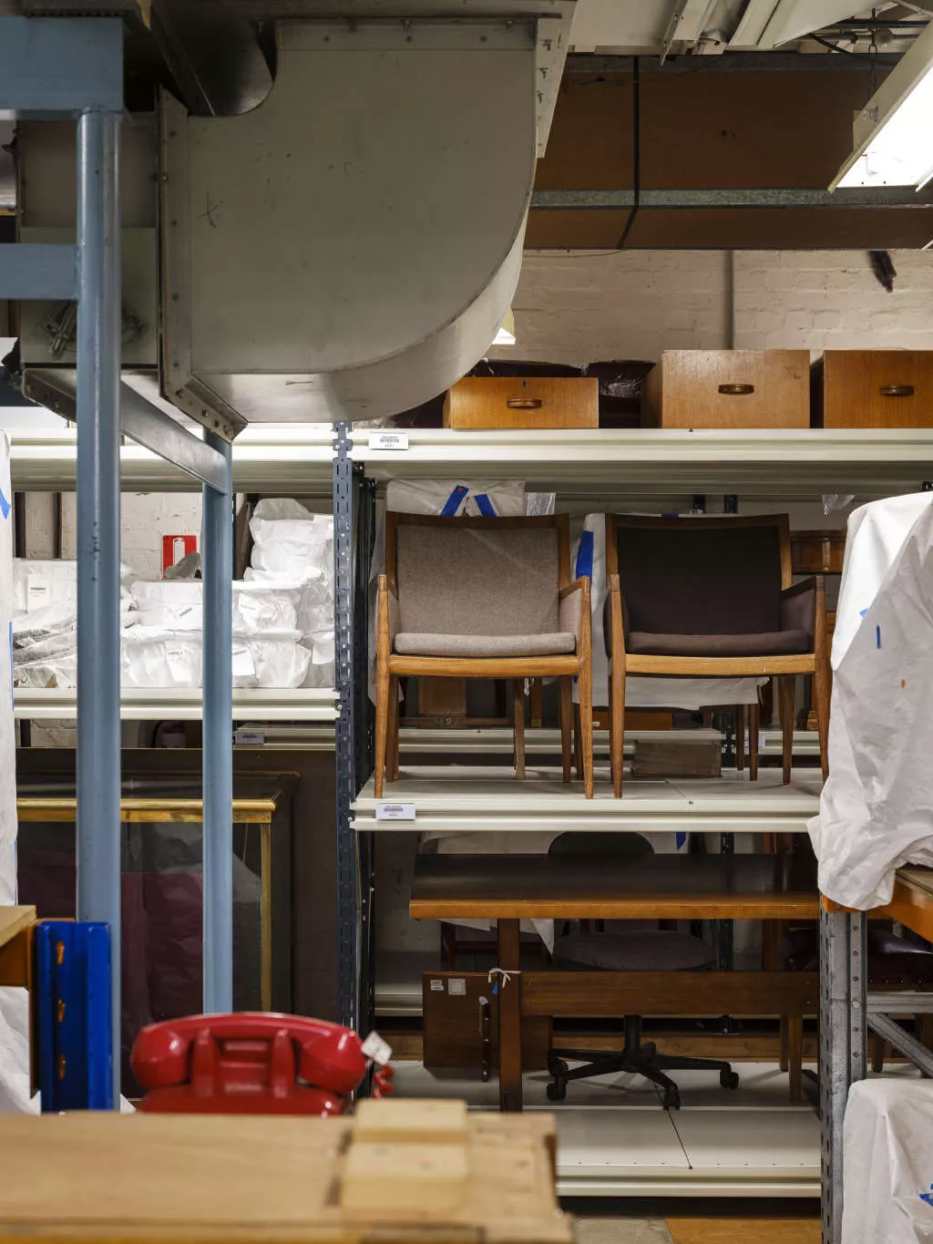 Storage underneath Old Parliament House, consisting of shelving with chairs, drawers and a desk stacked neatly on the shelving. Storage underneath Old Parliament House, consisting of shelving with chairs, drawers and a desk stacked neatly on the shelving.