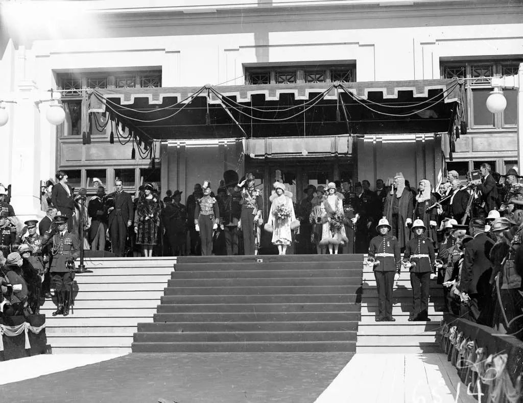 Dame Nellie Melba stands at the top-left of the steps in front of Old Parliament House, singing to a large audience of guests.