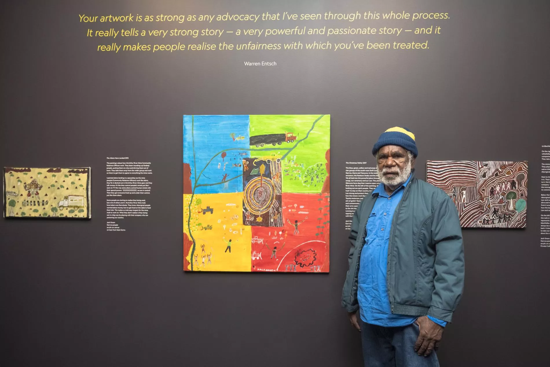 Jack Green stands in front of 3 of his paintings hung at MoAD. 