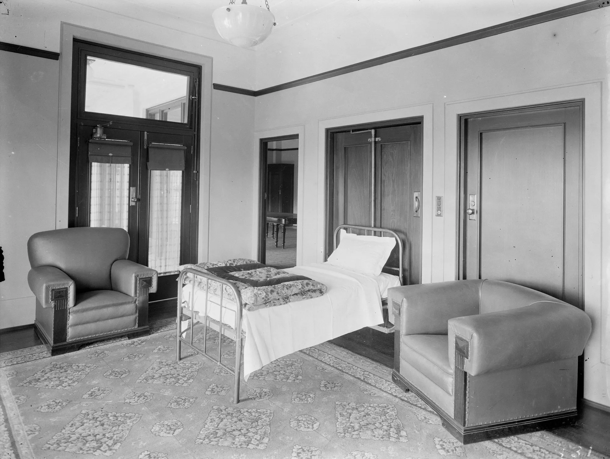 The Speaker's Room, Old Parliament House, with a bed folded out from a cupboard, covered with white sheets, a pillow and a folded floral quilt..