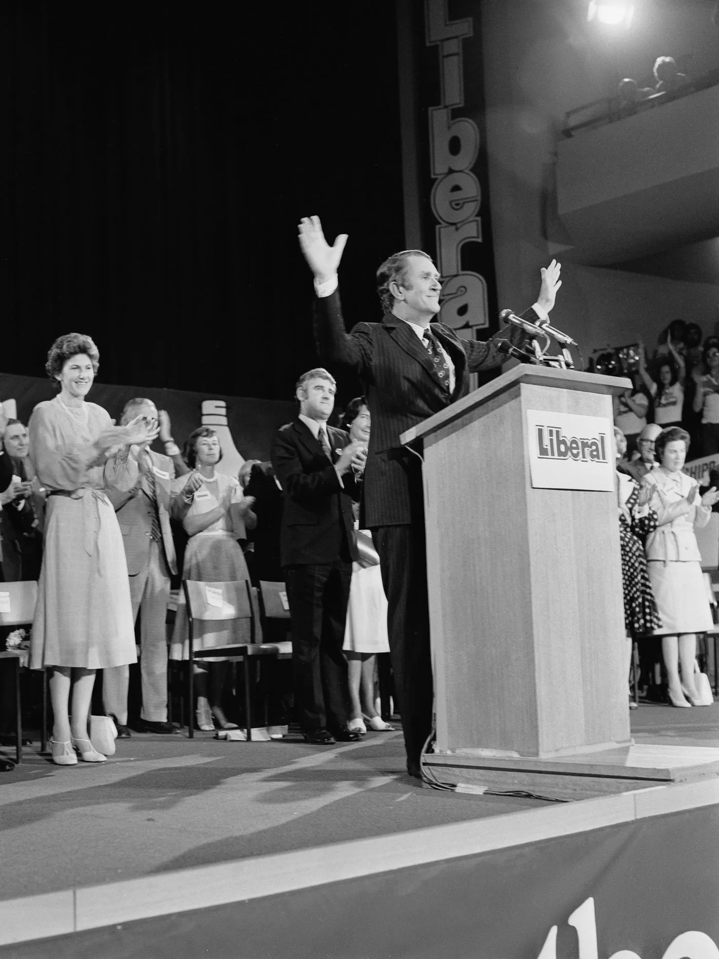 Malcolm Fraser stands at a podium on stage at a Liberal campaign rally.