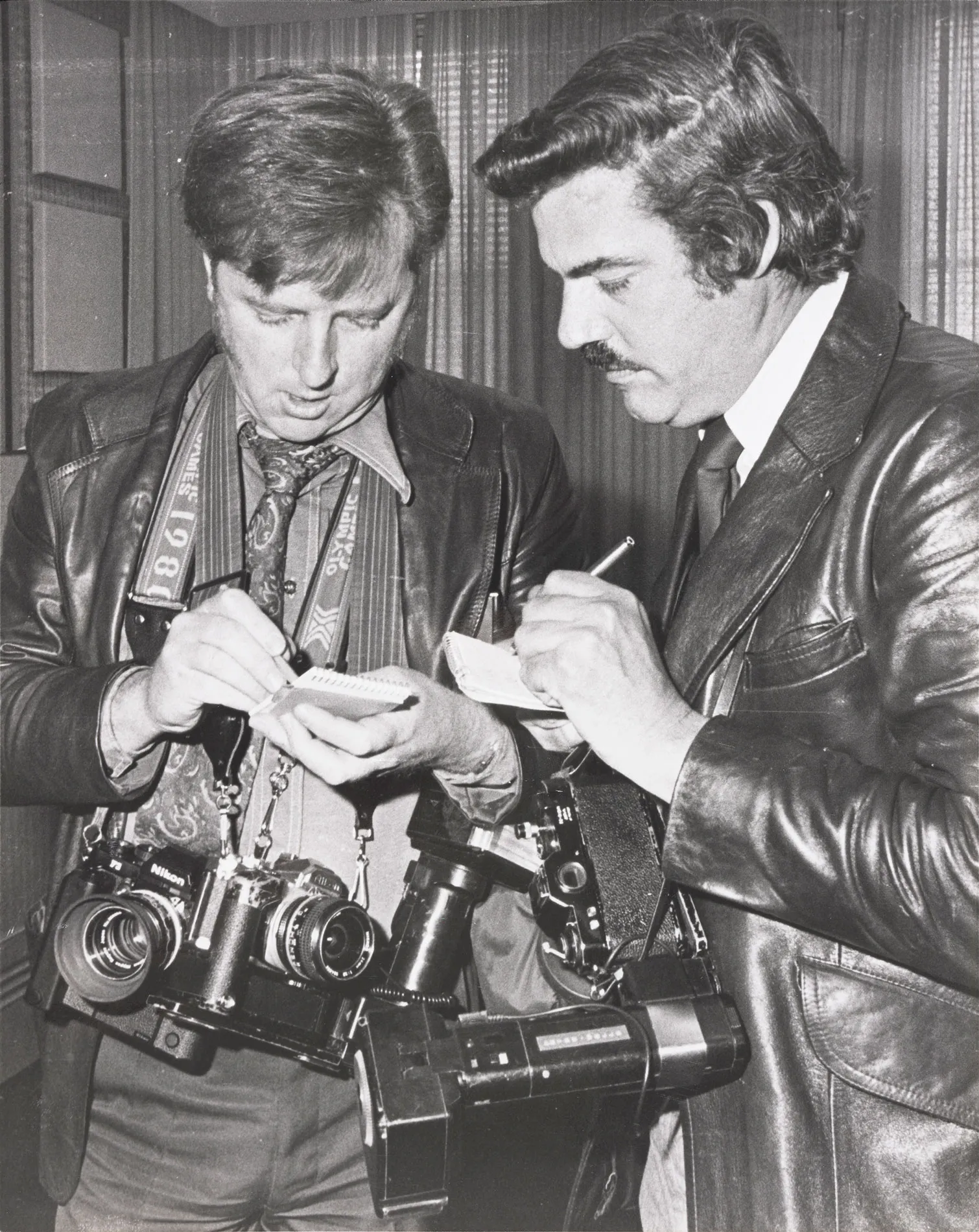 Photographer Bluey Thomson and another photographer taking notes.