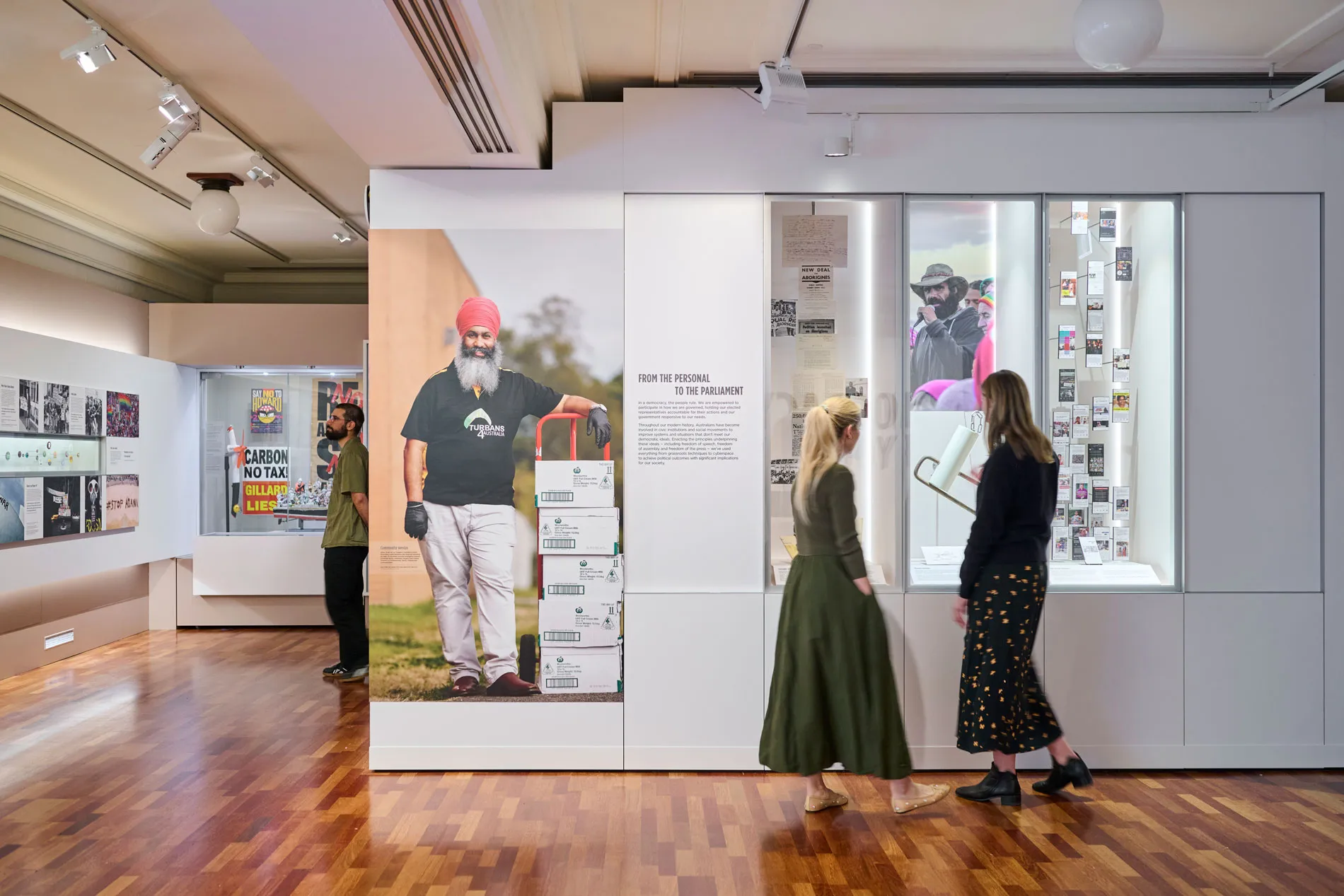 Three people read panels in the Democracy Are You In exhibit in Old Parliament House.