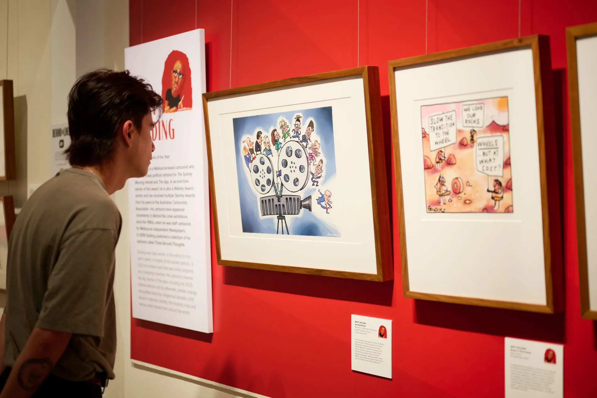 A man looks at framed cartoons in a political cartooning exhibition at Old Parliament House.