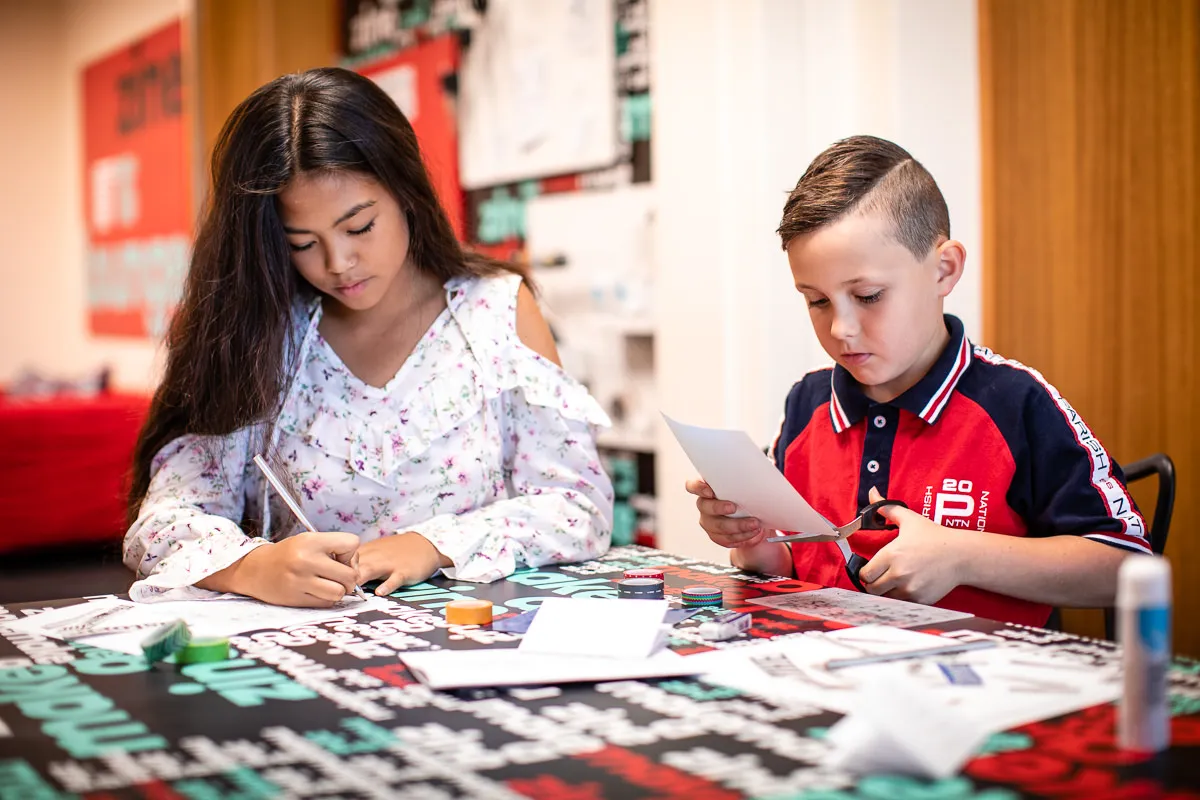Two kids write and craft in Old Parliament House.