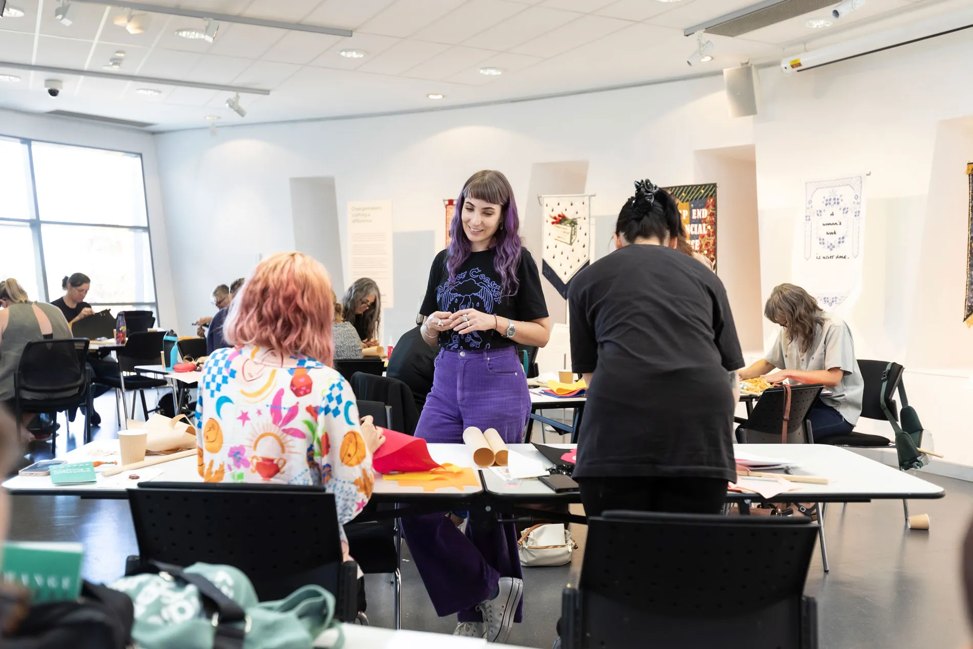 People seated at tables participating in a crafting workshop.