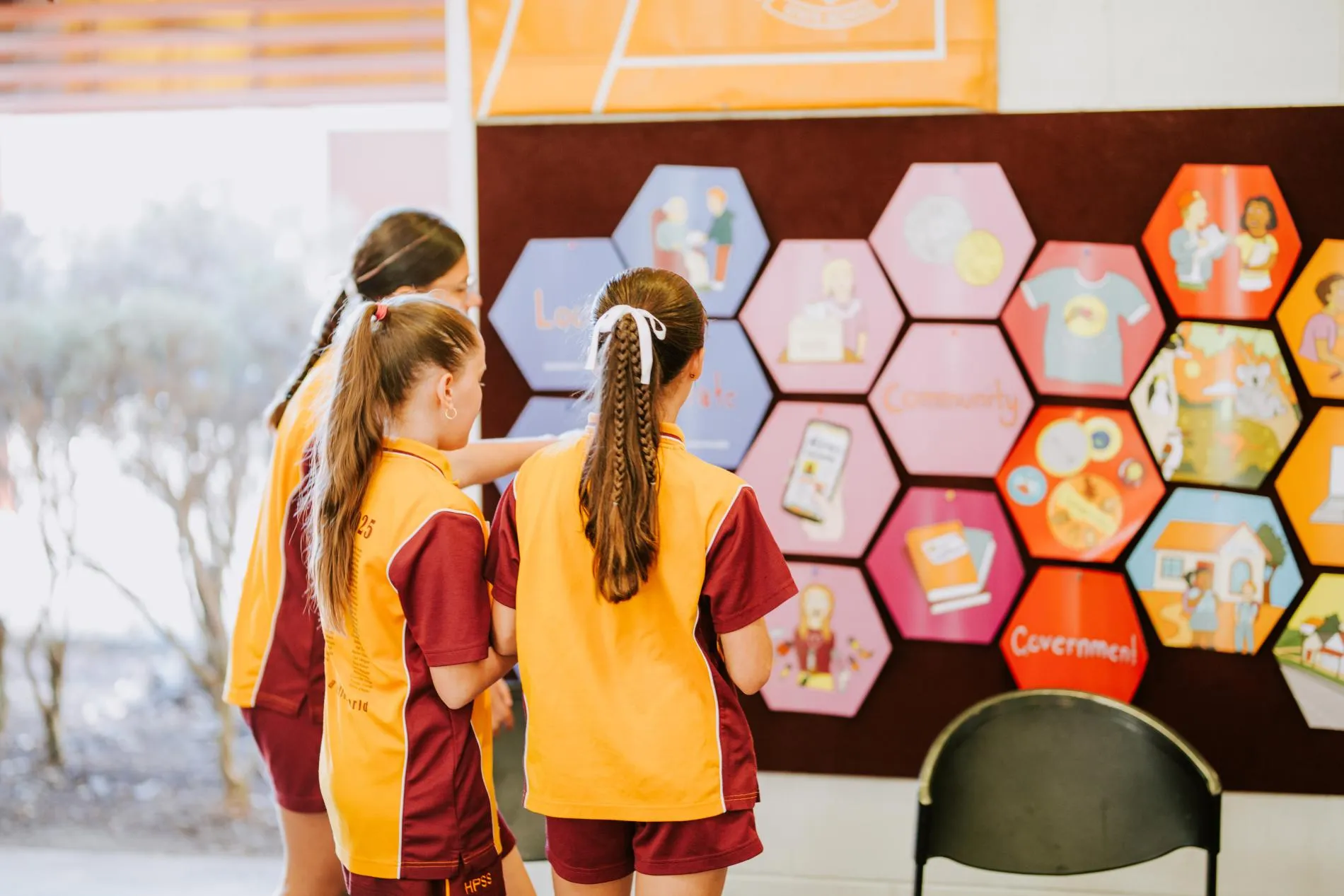 Some children looking at the pieces of Democracy in a Box mounted on a wall.