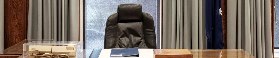 Former prime minister Bob Hawke's desk, complete with blue binder, ash tray, wooden box and old phone. Australian flag in the background.
