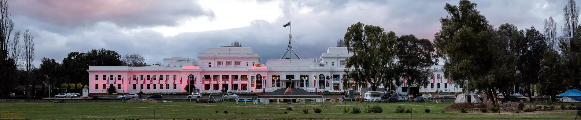The front of Old Parliament House in the evening lit up with pink lights.