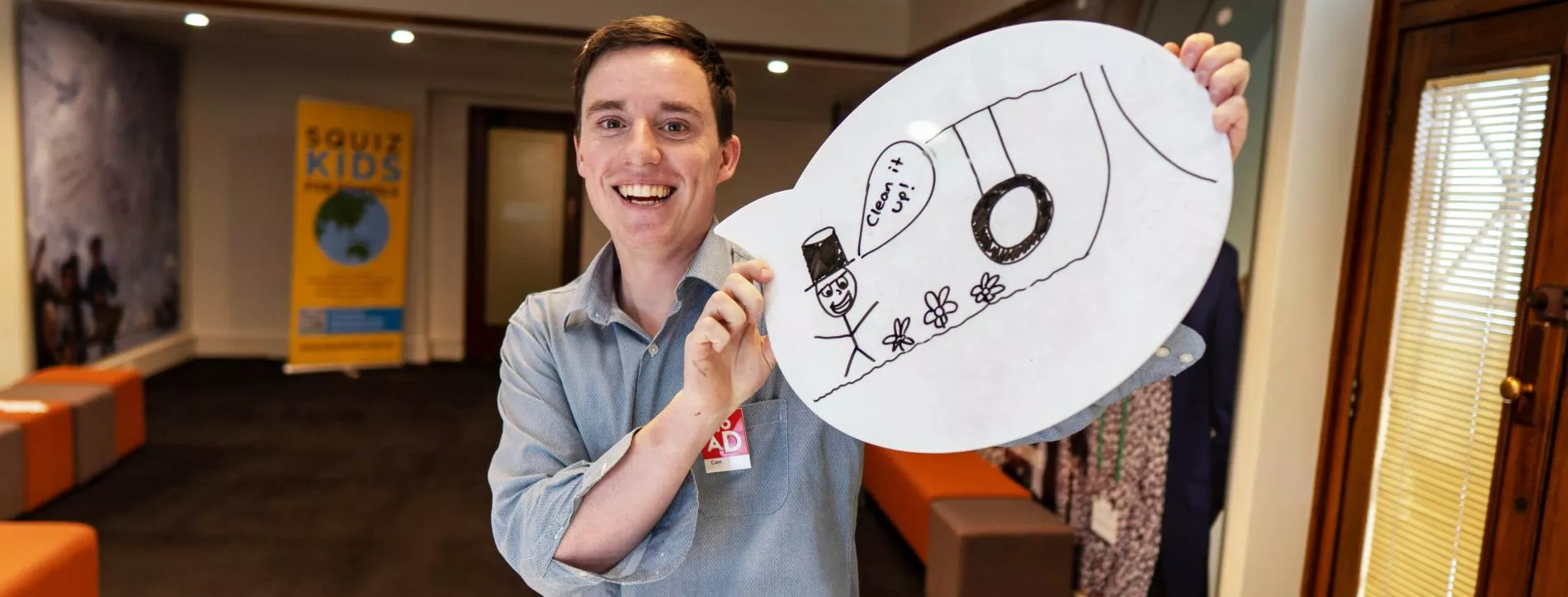 A person holds up a whiteboard speech bubble with a drawing on it.