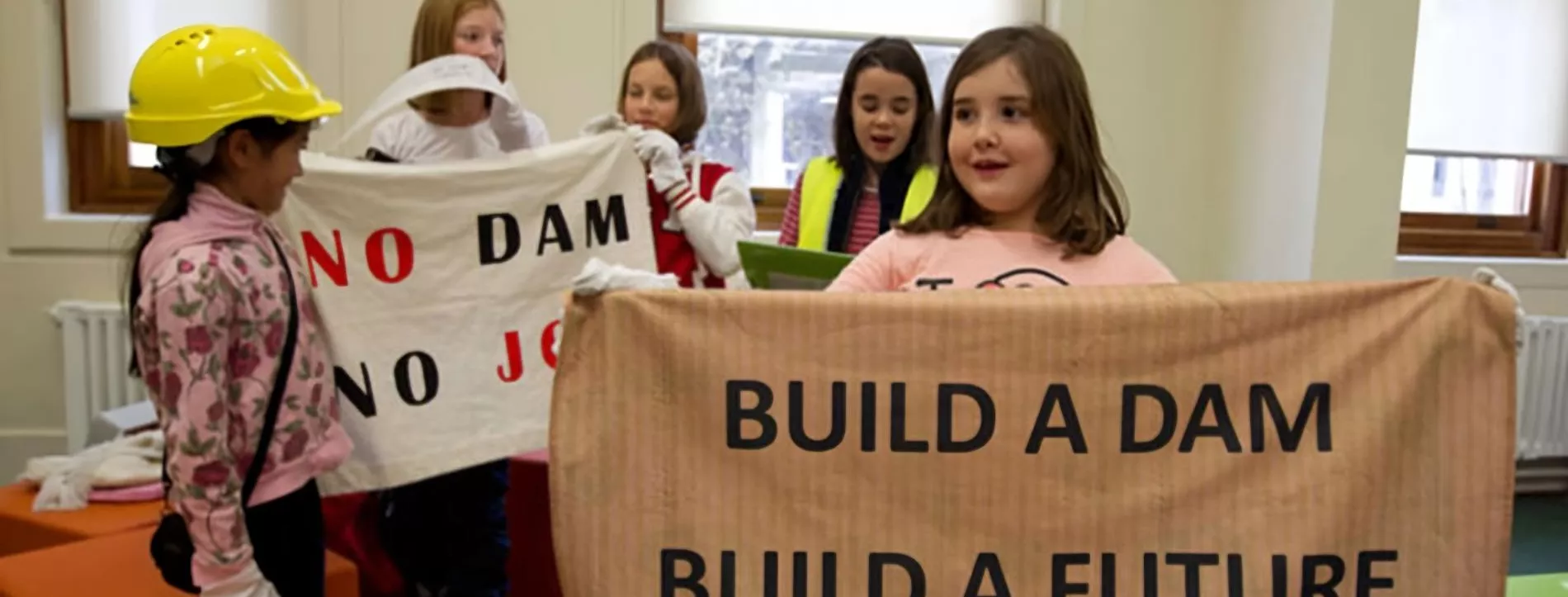 Primary school students hold up a sign which reads 'build a dam, build a future' inside Old Parliament House during an onsite program. 