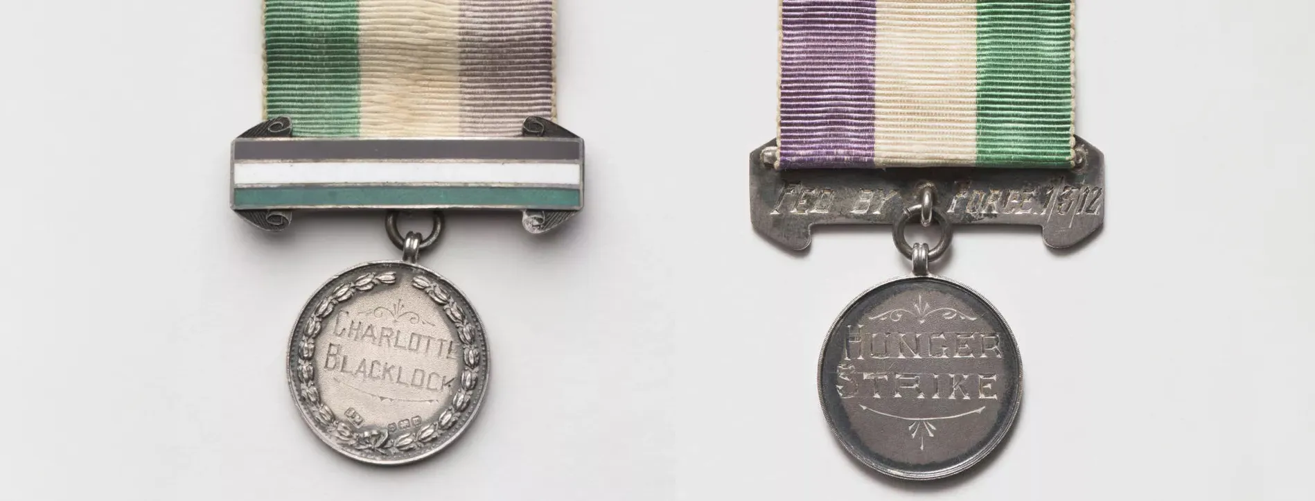 A round medal attached to a green, white and purple ribbon, etched onto the front the words 'For Valour' and 'Charlotte Blacklock', on the back 'Fed by force 1/3/12' and 'hunger strike'.