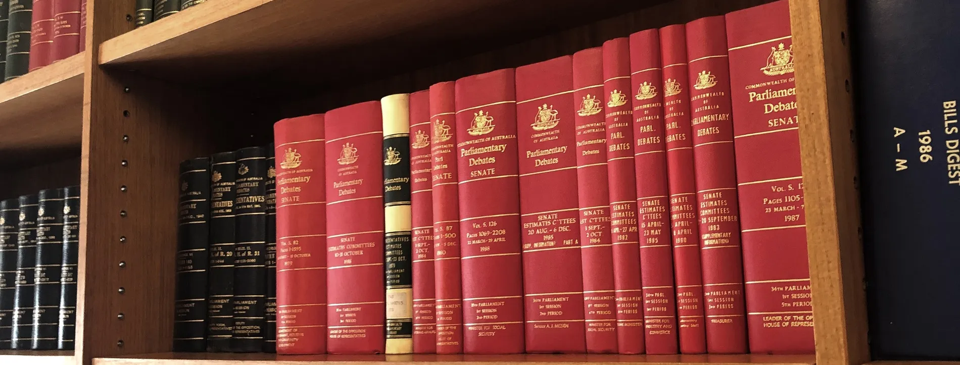 A row of red bound volumes on a shelf containing the proceedings of Senate Estimate committee hearings.