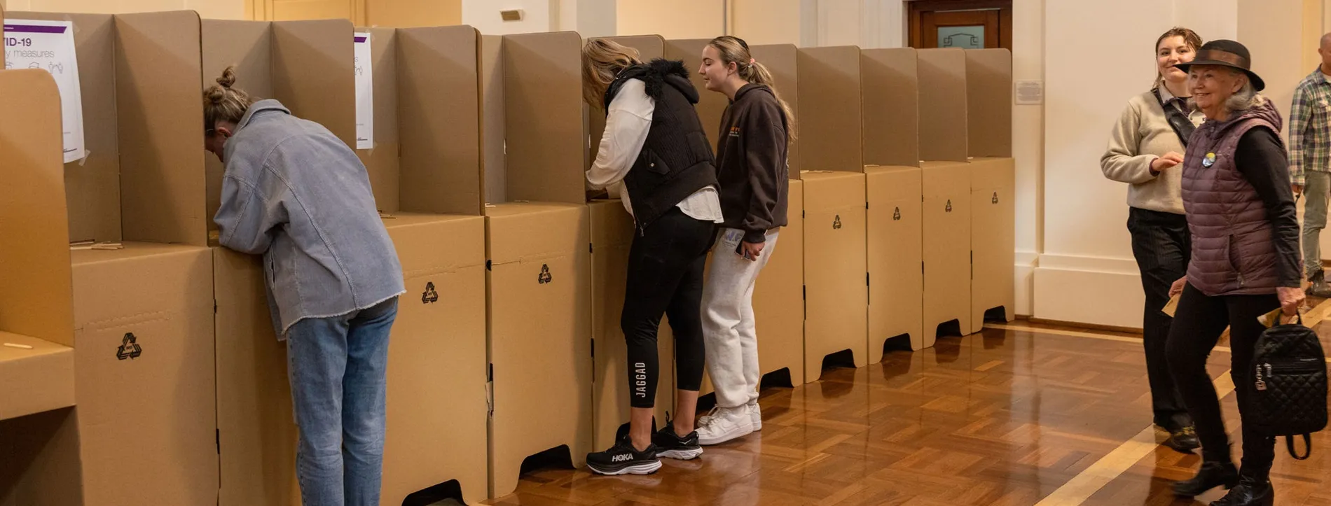 Three women standing at cardboard polling booths in King's Hall. 