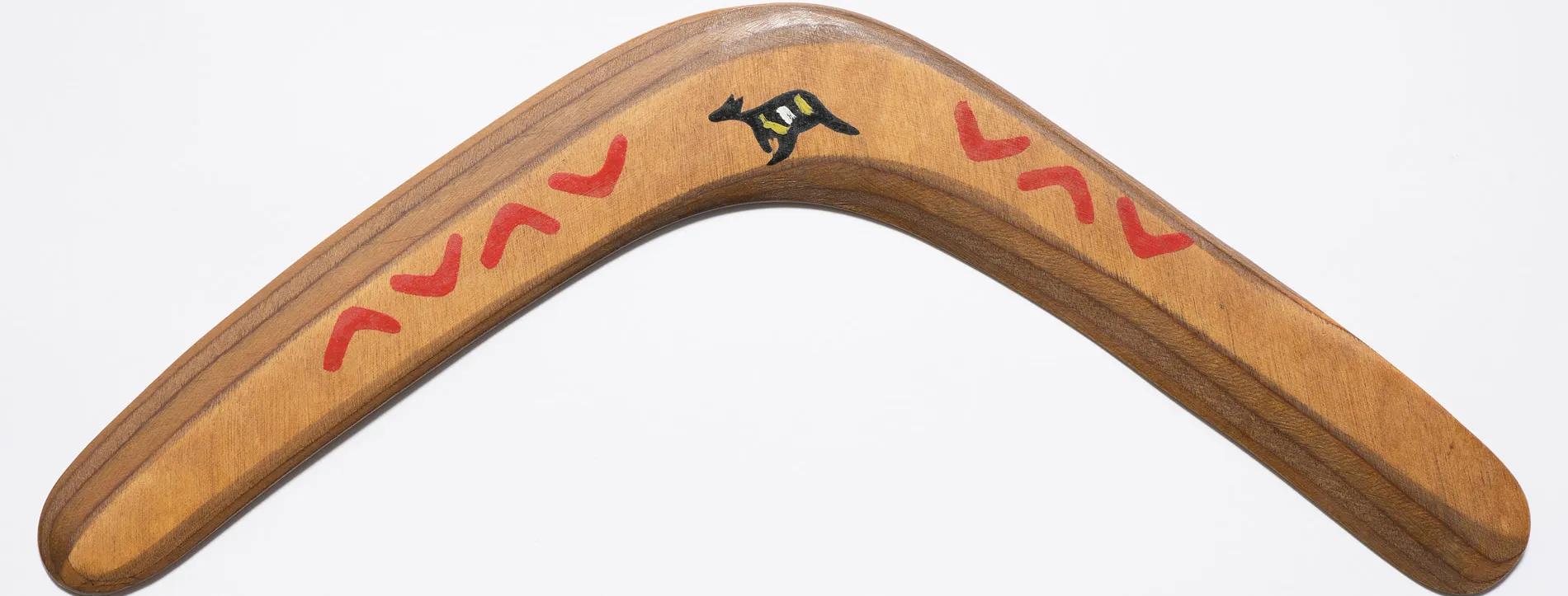 A wooden boomerang featuring a design of small boomerangs and a kangaroo.