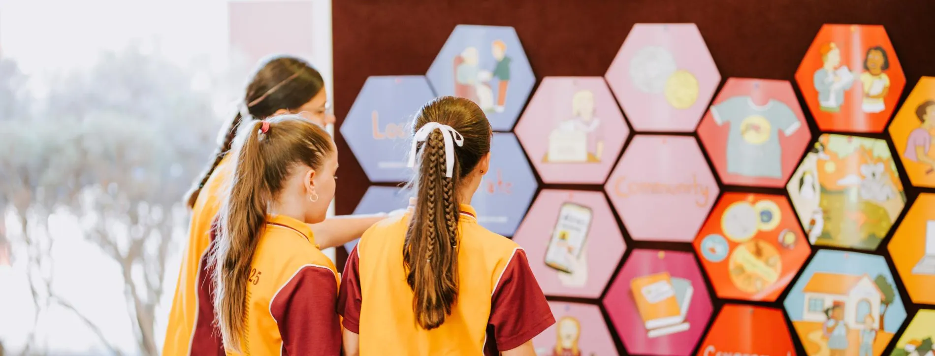 Some children looking at the pieces of Democracy in a Box mounted on a wall.