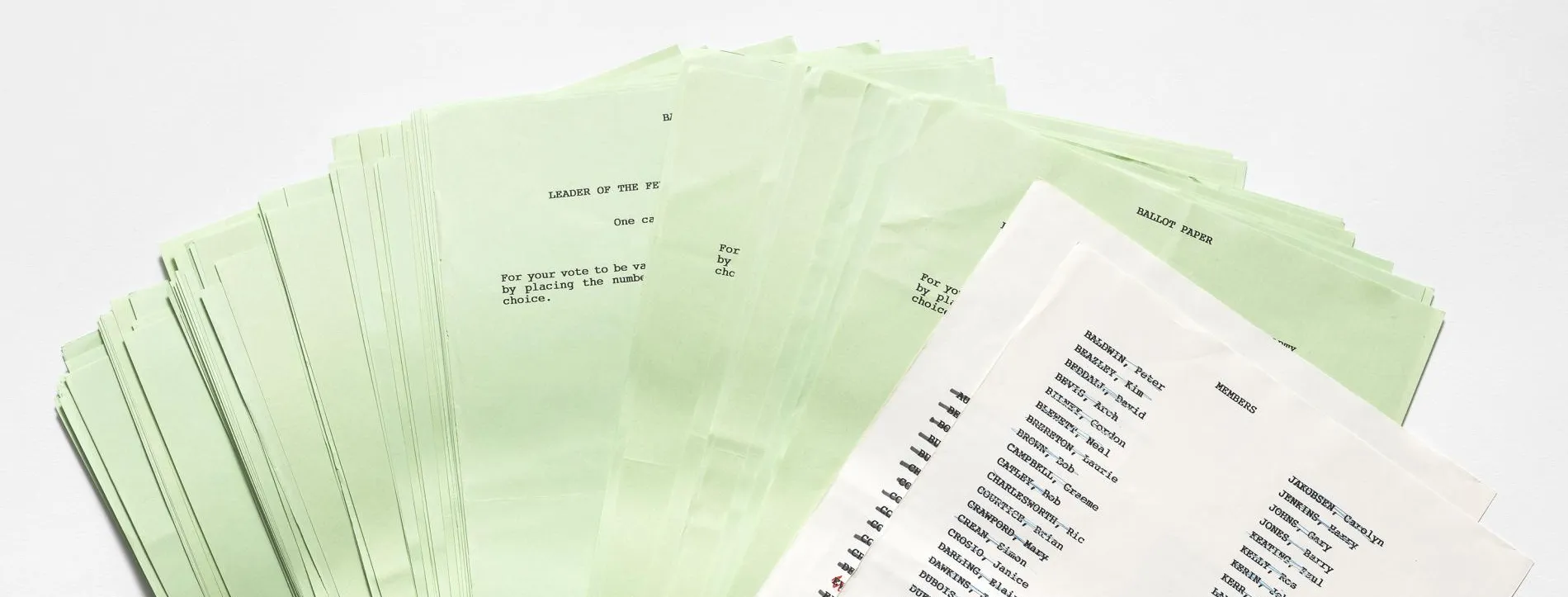 Green ballot papers fanned out on a white background, the front page is white and has a list of names under the title 'Members'.