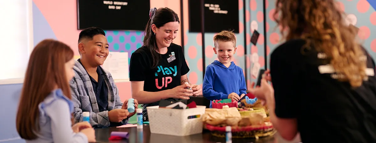 Three kids and two adults craft at a craft table at the Museum of Australian Democracy at Old Parliament House.