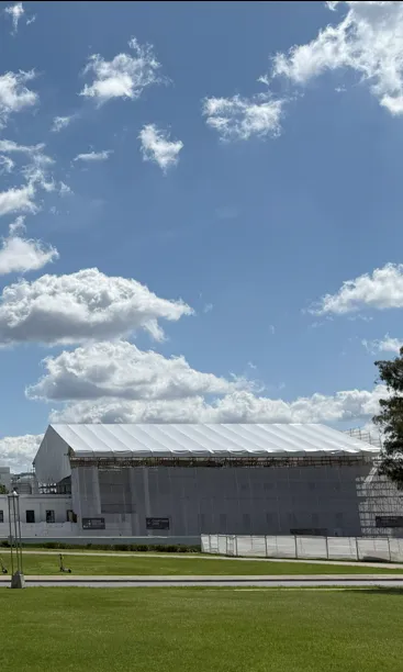 A view of the back of Old Parliament House, a long white building with a white scaffolding over one section of the roof and walls. 