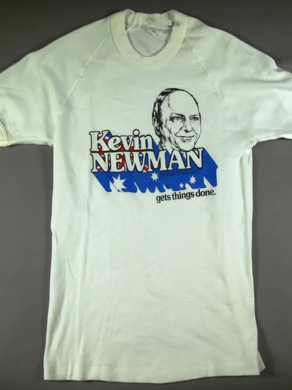 A white t-shirt with a caricature of a man's head, and the words 'Kevin Newman gets things done' with lettering shadow in the colours of the Australian flag.