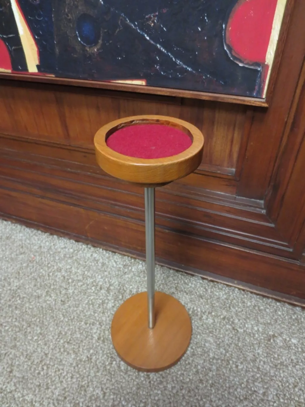 A round wooden stand with a metal pole with wooden base.