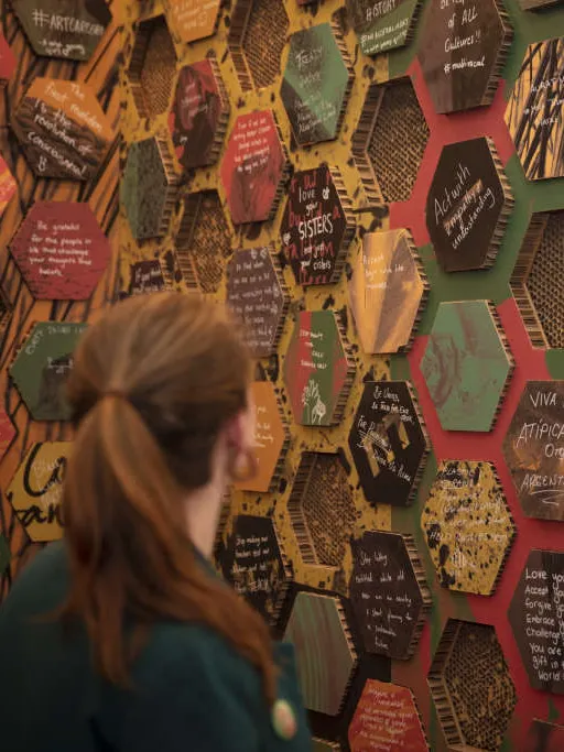 A visitor looking at a wall of honeycomb-styled blocks in the exhibition.