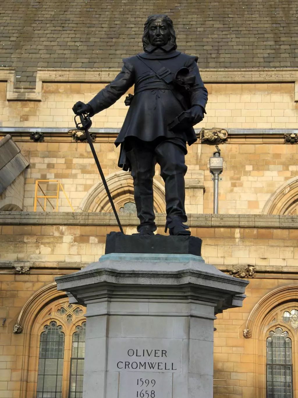 Statue of Oliver Cromwell holding a sword, on top of a sandstone column.