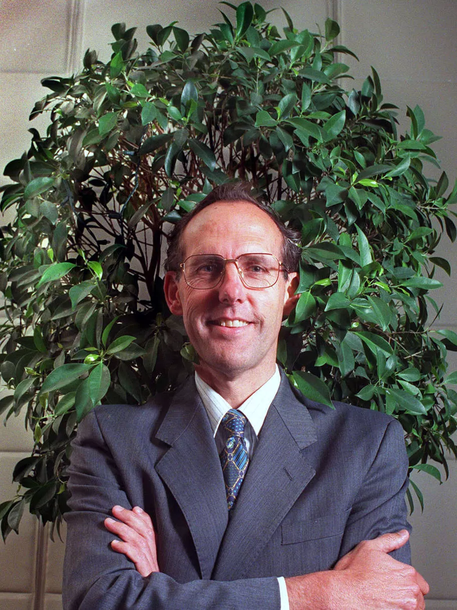 Dr Bob Brown, posing arms crossed in front of a small tree.