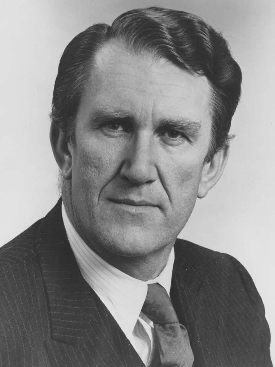 A man, Malcolm Fraser, wearing a pinstripe suit.